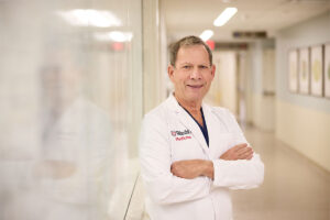 Man wearing white coat standing in hospital hallway