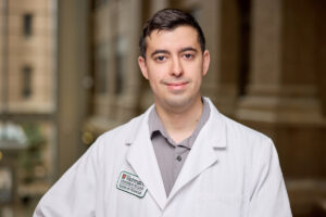 researcher in white coat poses for photo