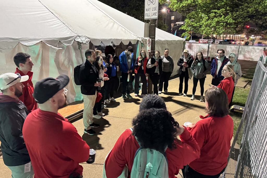 Volunteers stand in a circle near the medical tent, listening to instructions