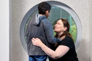Image of smiling woman kneeling, hugging child