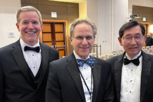 Three faculty members in tuxedos at event