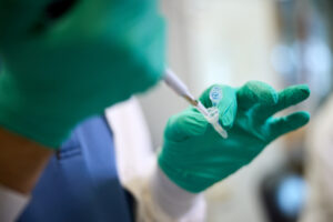 dropper in gloved hands in science lab