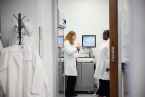 Researchers in white coats are shown conversing through a doorway.