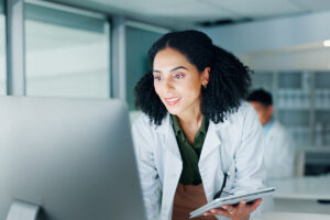 Woman standing, looking at computer with lab in background