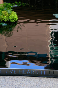 A closeup image of the infinity pool, showing the words, "I've heard it..." from an Emily Dickenson poem that's inscribed around the platform overlooking the water’s edge.